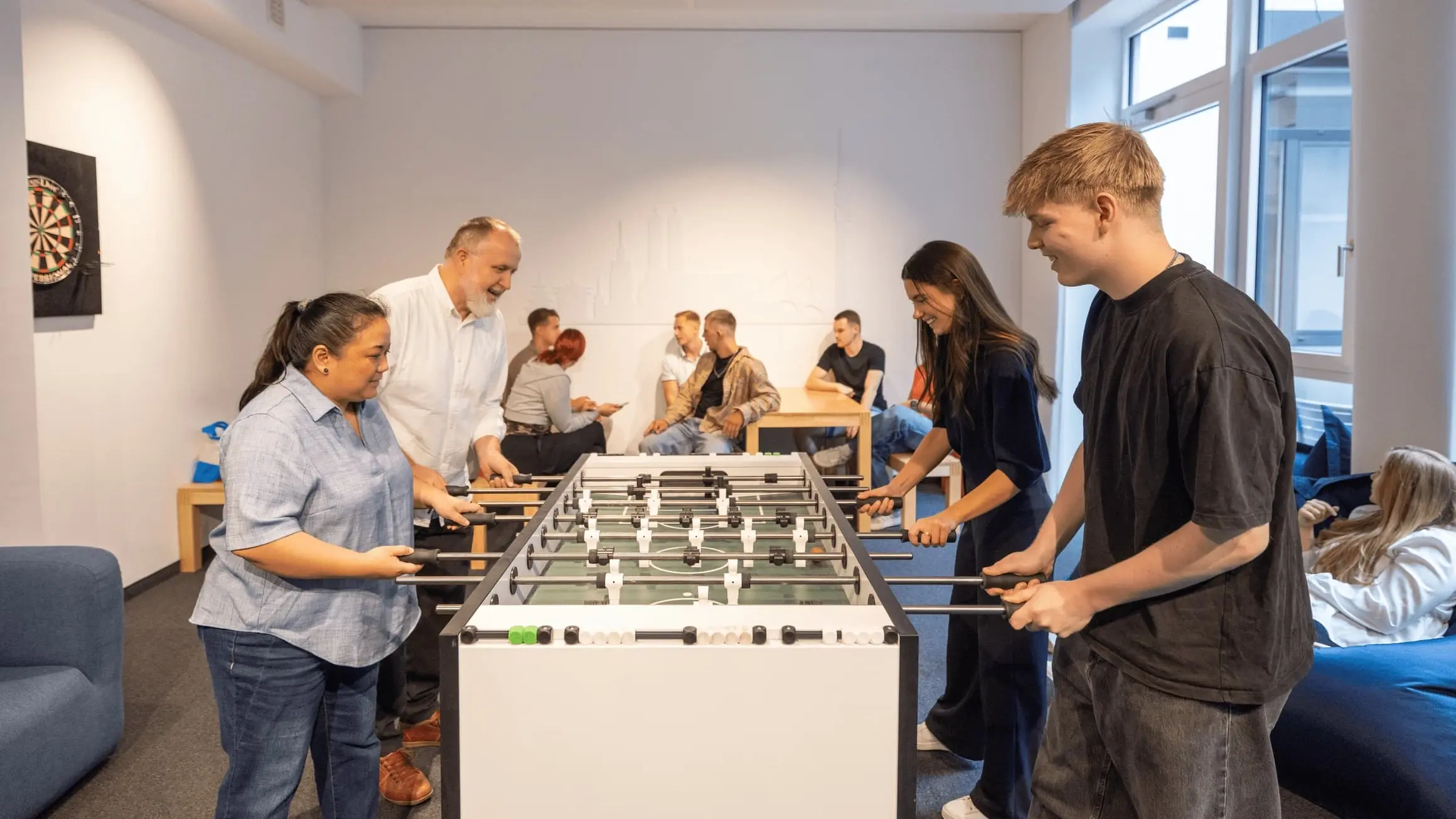 Kollegen im Aufenthaltsraum bei M-net, einige von ihnen am Tischfußball