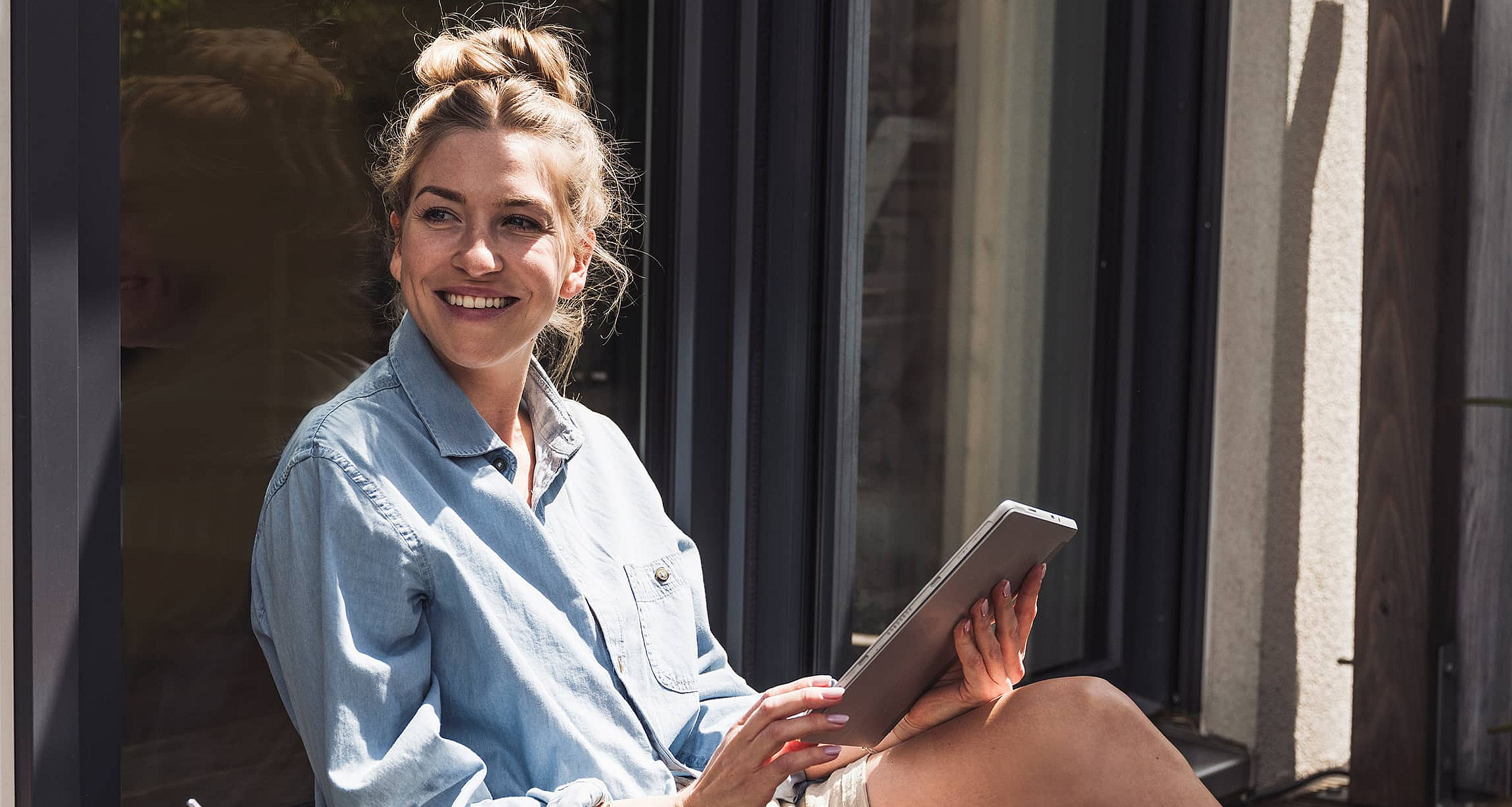 Eine Frau sitzt im Freie mit dem Tablet in der Hand