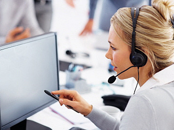 Kundenberater mit Kopfhörern vor einem Bildschirm im Gespräch