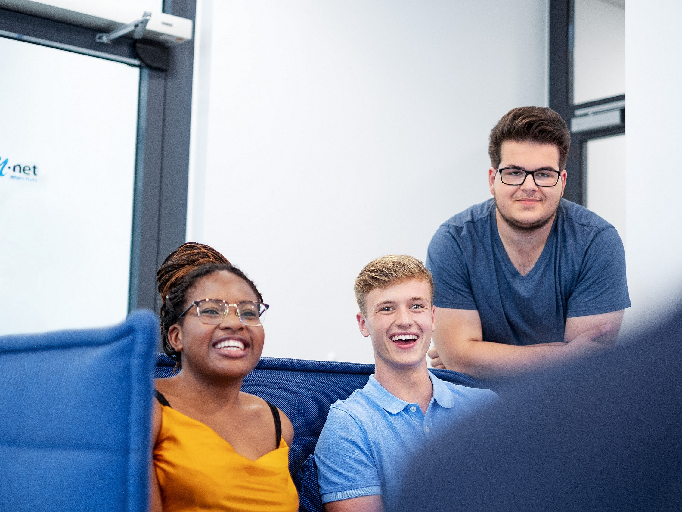 Azubis sitzen am M-net Empfang zusammen und lachen