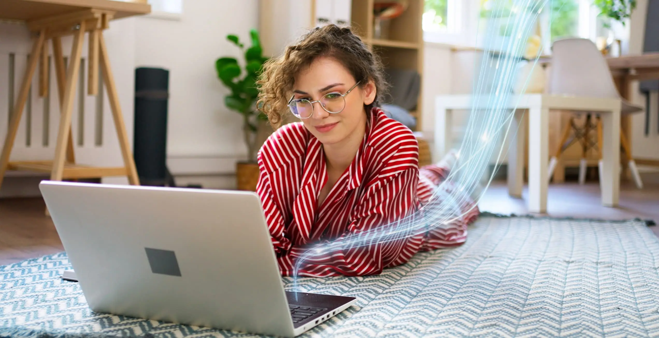 Eine Frau liegt auf dem Teppich und schaut in einen Laptop